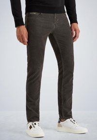 Jeans in denim grigio scuro slim-fit con una finitura testurizzata. Presentano dettagli di cucitura sottili e tasche anteriori con zip. Abbinati a sneaker bianche.