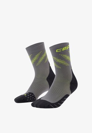 Paar grauer und schwarzer Sportsocken mit gelben Akzenten und Markenaufdruck, die eine strukturierte Strickart und gepolsterte Sohlenbereiche zeigen.