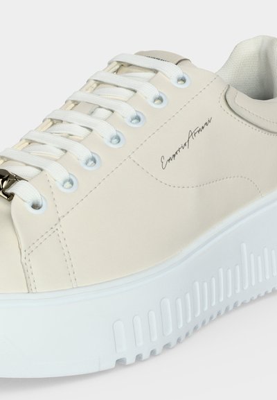 Αθλητικό παπούτσι από κρεμ χρώματος δέρμα με λευκή χοντρή σόλα, λευκά κορδόνια, μεταλλικά κορδόνια και λογότυπο "Emporio Armani" στη πλευρά.