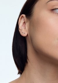 Złote kolczyki w kształcie pszczoły, z delikatnymi skrzydłami wykończonymi białą emalią i czerwonymi akcentami, osadzone w bezpiecznym zapięciu na plecy.