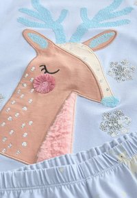 Light blue pajama top featuring an embroidered reindeer with pink and beige accents, textured fur, and light blue sequined antlers.