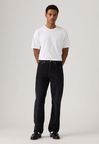 Zwarte corduroy herenbroek met een recht gesneden pasvorm, gecombineerd met een aansluitend wit katoenen T-shirt. Gladde textuur en een vijf-pocket ontwerp.