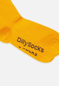 Żółte bawełniane skarpetki z żebrowaną teksturą i napisem "Dillysocks" w ciemnoszarym kolorze po boku. Drobno dziane i miękkie.