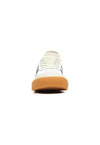 Zapatillas blancas con rayas negras, suela de goma texturizada, diseño con cordones y un mínimo de logotipo en la lengüeta. Adecuadas para un uso casual.
