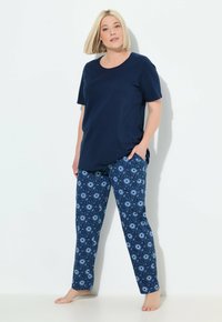 Donkerblauw katoenen t-shirt met korte mouwen en een ontspannen pasvorm, gecombineerd met gestreepte pyjamabroek met donkere en lichte blauwe cirkelvormige ontwerpen.