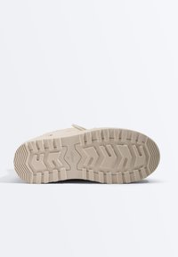 Semelle de botte beige avec un profond motif de bande de roulement, des rainures rectangulaires et en zigzag, et des marquages en relief de taille et de marque au centre.