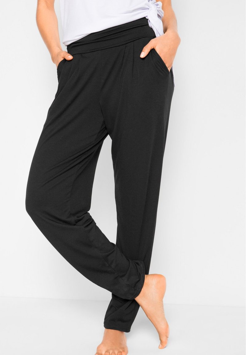 Pantaloni lounge neri con una fascia in vita ampia e tasche laterali, realizzati in un tessuto morbido ed elastico; presentano una vestibilità rilassata e gambe affusolate.