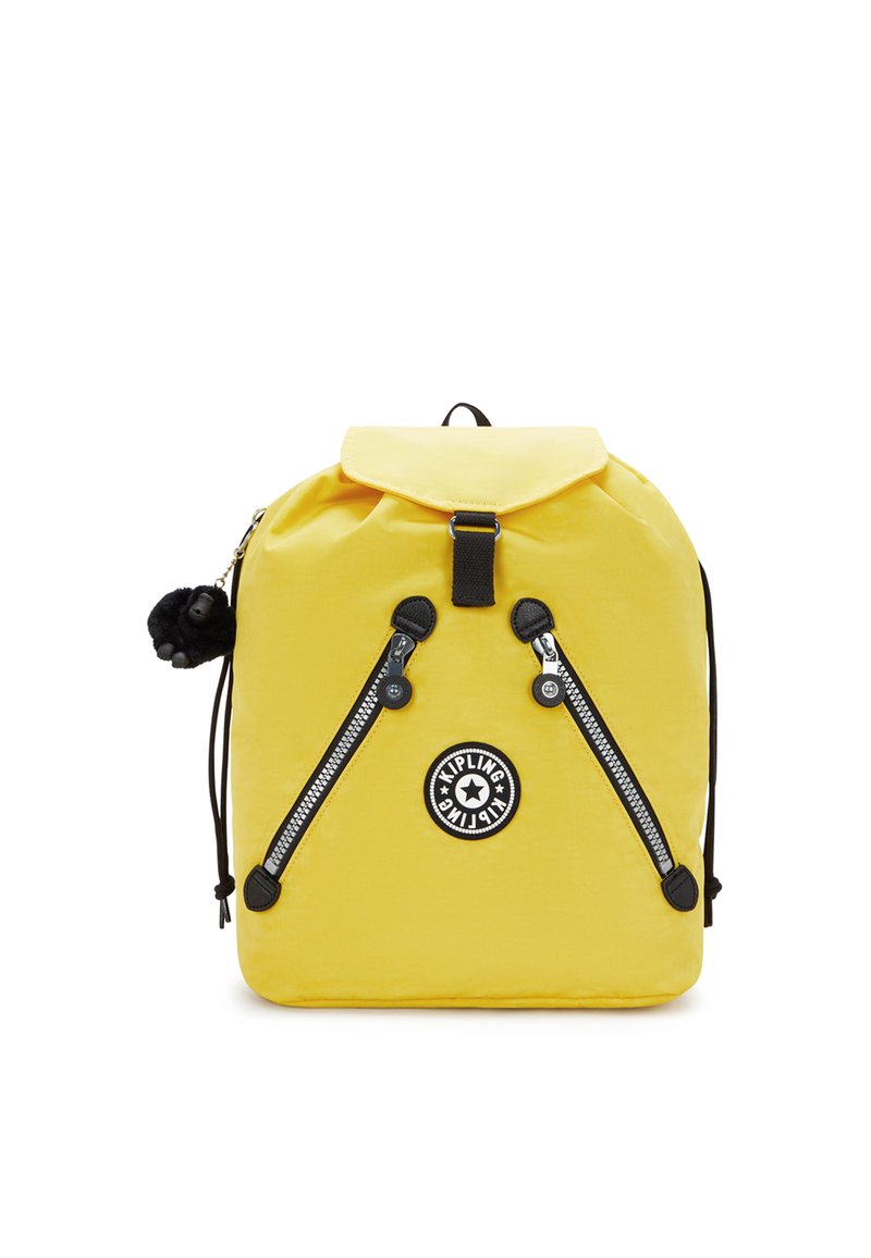 Gul nylonryggsäck med lock, svarta dragkedjeaccenter, en rund logopatch och en plyschapa nyckelring fäst.