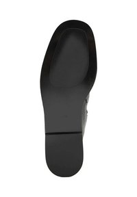 Suela de zapato negra con una textura suave y una forma ligeramente curvada. Presenta un patrón acanalado hacia la parte delantera y un tacón plano.