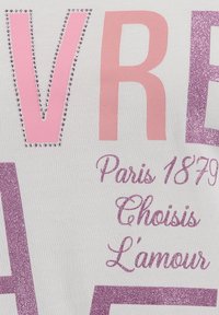 Vêtements blancs avec un grand texte rose et paillettes violettes. Des strass décoratifs soulignent certaines lettres. Le texte comprend "Paris 1879" et "Choisis L'amour."