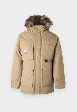 Bež parka jakna s kapuljačom obloženom krznom, višestrukim prednjim džepovima, zatvaračem i pojačanim manžetama. Ima okrugli logotip na prsima.
