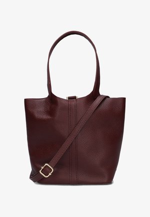 Sac fourre-tout en cuir bordeaux avec une texture douce, des poignées courtes et une bandoulière amovible. Présente une couture verticale sur le devant.