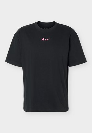 T-shirt noir à manches courtes Nike avec col rond, présentant de petits logos rose d'enceinte en mode silencieux et swoosh centrés sur la poitrine.