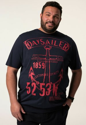 Camiseta casual de color azul marino con mangas cortas, que presenta un gráfico de ancla náutica roja, detalles textuales y un diseño de corte relajado.