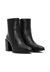 Bottines noires en cuir avec un orteil pointu et un talon épais. Elles présentent une fermeture éclair sur le côté et une texture lisse.