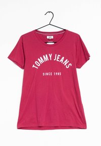 Punainen puuvillapaita, jossa on pyöreä kaula-aukko ja lyhyet hihat. Etupuolella lukee "TOMMY JEANS" kaarevasti "SINCE 1985" valkoisella tekstillä.