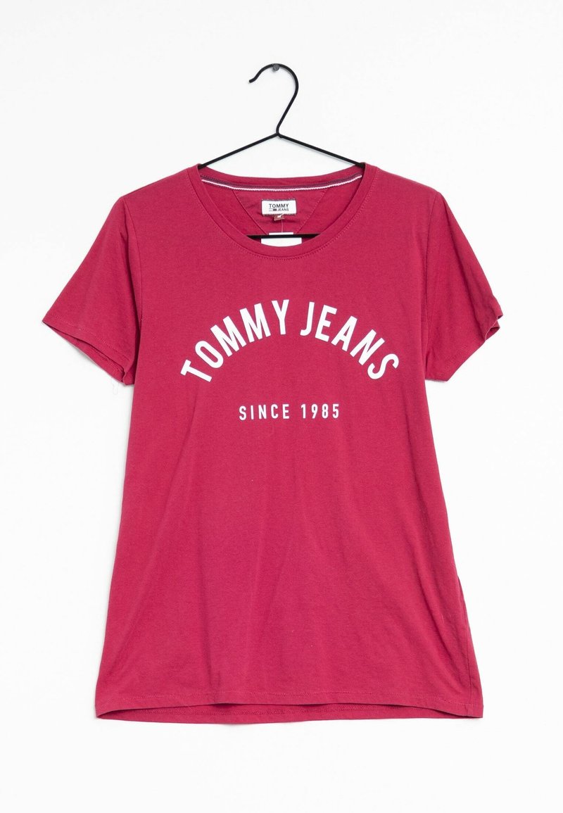 Punainen puuvillapaita, jossa on pyöreä kaula-aukko ja lyhyet hihat. Etupuolella lukee "TOMMY JEANS" kaarevasti "SINCE 1985" valkoisella tekstillä.