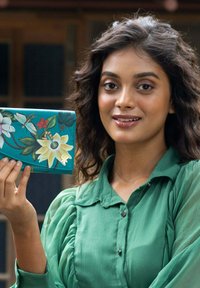 Teal portemonnee met bloemenpatroon, featuring witte en gele bloemen, groene bladeren, en rode accenten. Gemaakt van een glad materiaal.