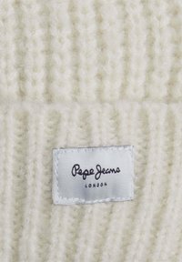 Suéter blanco de punto con tejido texturizado. Presenta una etiqueta cosida que dice "Pepe Jeans London" en una escritura negra sobre un fondo blanco.