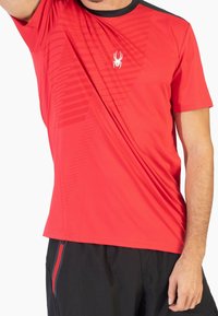 Rode sportieve t-shirt gemaakt van lichtgewicht stof. Heeft een zwarte kraag en een spinnenlogo, met een subtiel gestreept patroon aan de voorkant.