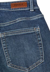 Blauwe denim spijkerbroek met een bruin leren label met de tekst "ONLY" op de tailleband, met een achterzak en een beetje contrasterende stiksels.