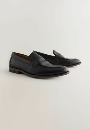 Schwarze Lederloafers mit strukturierter Oberfläche, ausgestattet mit einer gestickten Vorderseite und einer braunen Ledersohle. Klassisches Slipper-Design.
