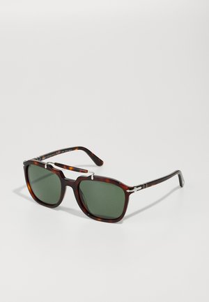 Lunettes en écaille de tortue avec verres verts, forme rectangulaire, accents argentés sur la monture et finition polie.