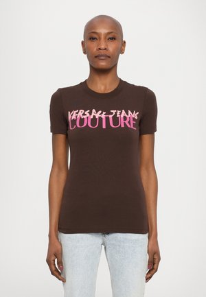 Bruine korte mouw t-shirt van katoen, met roze tekst "VERSACE JEANS COUTURE" over de borst. Fitted ontwerp met een ronde hals.