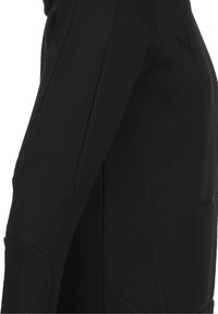 Felpa nera sportiva con tessuto liscio e pannelli in rete testurizzati. Include una tasca con zip e vestibilità elastica. Logo sul lato sinistro in alto.