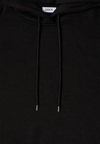 Sudadera negra de tejido suave que presenta un bolsillo canguro en la parte frontal, cordones con puntas metálicas y un pequeño logo en relieve en el pecho.