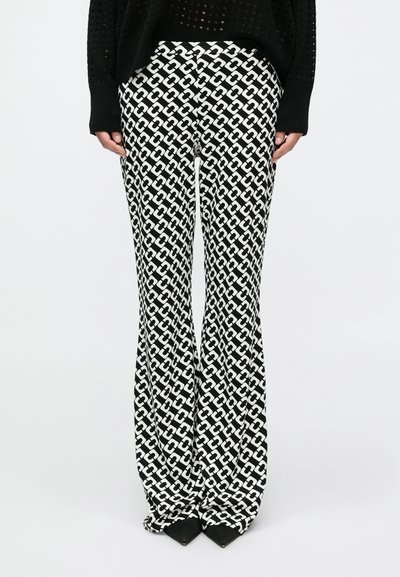 Pantalon évasé noir et blanc avec un motif chaîne géométrique. Confectionné dans un tissu doux, présentant une taille haute et une texture lisse.