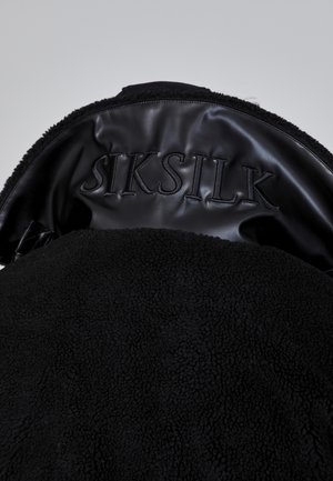 Black shearling jacket with a plush texture; features a black leather interior with embossed "SIKSILK" logo.