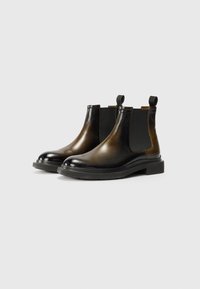 Bottines Chelsea en cuir noir avec des panneaux élastiques et des languettes, présentant un bout rond, une semelle épaisse et une texture lisse.