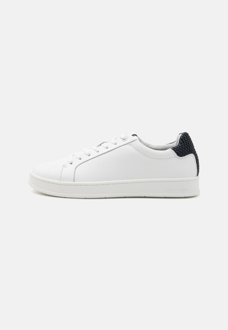 Sneaker bianca in pelle con finitura liscia, punta tonda, tallone in tessuto blu navy a contrasto e suola in gomma bianca. Presenta una chiusura con lacci piatti.