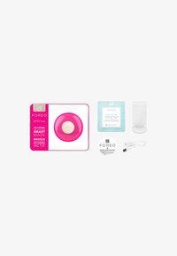 Foreo UFO mini i stark rosa, rund med texturerad yta; inkluderar mask, vit laddkabel och informationskort.