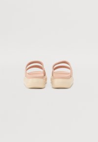 Roze sandale na slip-on s tri remena i debelim, kremastim đonom. Materijal izgleda glatko s mat završnom obradom.