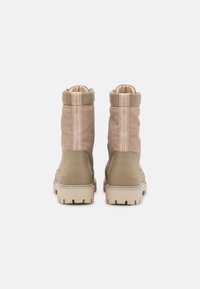 Beige Knöchelstiefel mit einem strukturierten Canvas-Obermaterial, einem kontrastierenden Gummiabsatz und -besatz, akzentuiert durch ein Banddetail auf der Rückseite.