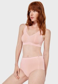 Lichtroze naadloze bralette en hooggesneden broekje set in een zachte stof. De bralette heeft een V-hals en brede bandjes; het broekje heeft een gladde tailleband.