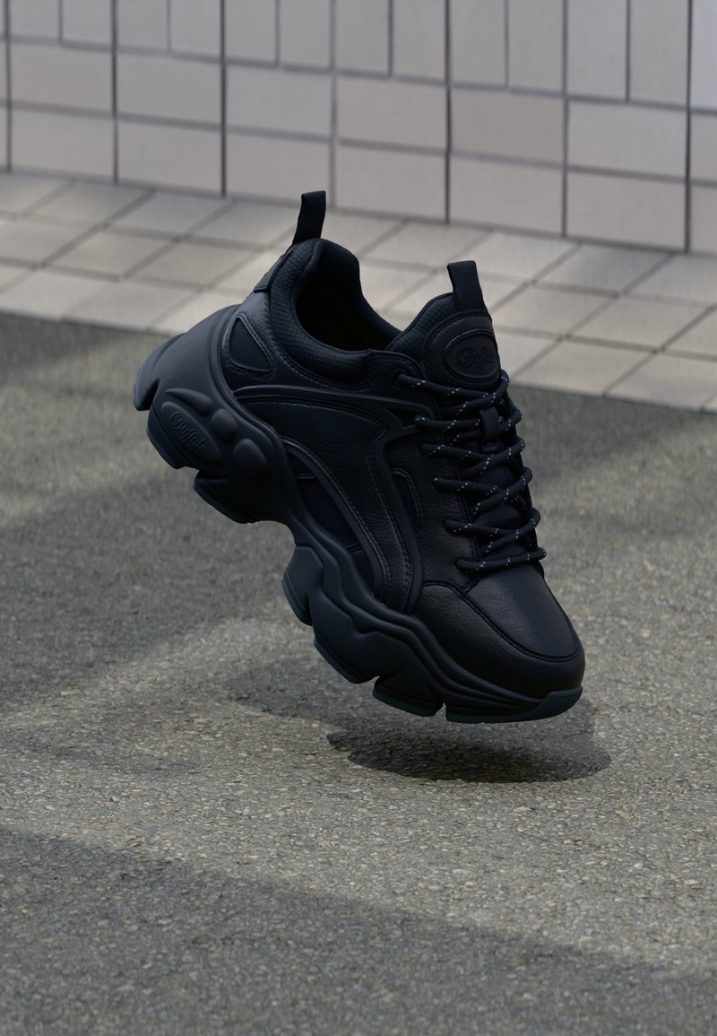 Sort atletisk sneakers med overdel i struktureret læder, tyk gummisål, snørebåndsdesign og fremtrædende polstring med unik form.