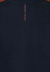 Marineblåt stof med lodret orange tekst "HACKETT SPORT" nær halsudskæringen og en orange stribe detalje ved den øverste kant.