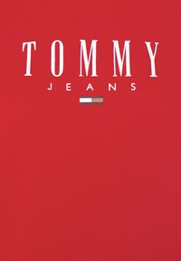 Červené bavlněné tričko s nápisem "TOMMY" bílými tučnými písmeny a "JEANS" pod ním, s malým modrým, bílým a červeným logem.