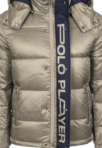 Padded jacket v metalické béžové barvě s námořnickým předním zipem a textem 'POLO PLAYER'. Obsahuje cvakací knoflíky a boční kapsy.