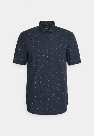 Camisa de manga corta, con botones, en azul marino con pequeños patrones blancos y rojos dispersos. Presenta un cuello estándar y botones negros.