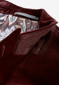 Burgundijska baršunasta ovratnica s uzorkom unutarnjeg obloga s paisley motivima u nijansama smeđe, zelene i krem boje. Tekstura s glatkim finišem.