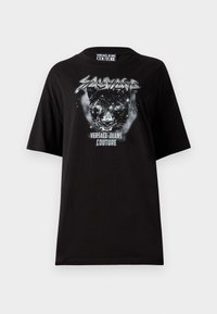 Svart oversized t-skjorte laget av bomull, med et grafisk bilde av en panter og teksten "Sauvage Versace Jeans Couture" på forsiden.
