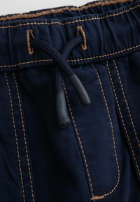 Granatowe szorty bawełniane z elastycznym paskiem w talii i sznurkiem, z kontrastującymi beżowymi przeszyciami oraz dwiema przednimi kieszeniami.