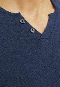 Maglione lavorato a maglia blu navy con scollatura a V, due bottoni neri sul collo e una consistenza morbida.