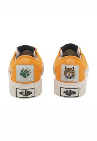 Narančaste platnene tenisice s bijelim potplatima. Moguće je vidjeti zakrpe medvjeda i tigra na stražnjoj strani, crne detalje i teksturirane gumene đonove.
