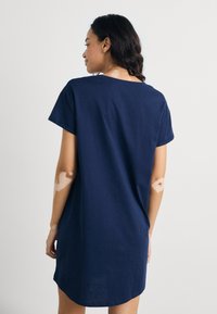 Marinblå bomulls-T-shirtklänning med korta ärmar, avslappnad passform och rundad nederkant. Slät textur, enkel design, inga synliga mönster eller detaljer.