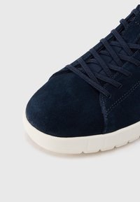 Σουέντ αθλητικό παπούτσι σε ναυτικό μπλε χρώμα με κορδόνια στο ίδιο χρώμα και λευκή υφασμένη ελαστική σόλα, εμφανιζόμενο σε κοντινό πλάνο από την μπροστινή πλευρά.